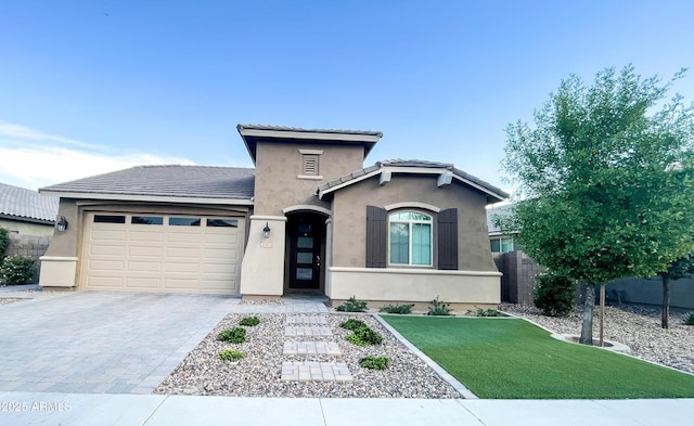 view of front of home with fence, a tile roof, stucco siding, decorative driveway, and a garage