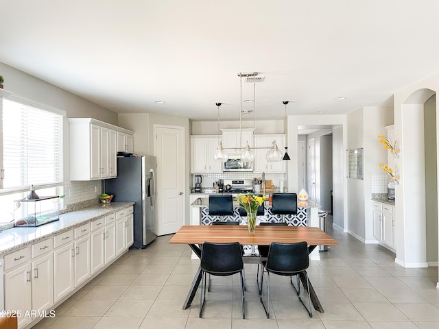 kitchen with hanging light fixtures, white cabinets, tasteful backsplash, and appliances with stainless steel finishes