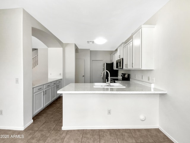 4229 E Betsy Ln, Gilbert, AZ 85296 - kitchen with stainless steel microwave, a peninsula, black range with electric stovetop, tile patterned floors, and white cabinets