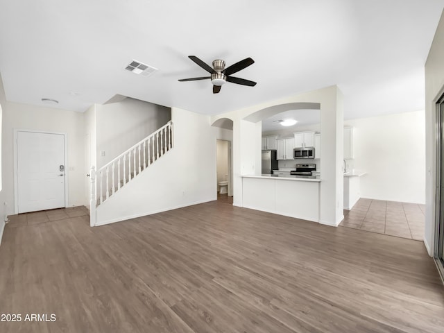 4229 E Betsy Ln, Gilbert, AZ 85296 - unfurnished living room featuring a ceiling fan, stairway, wood finished floors, and arched walkways