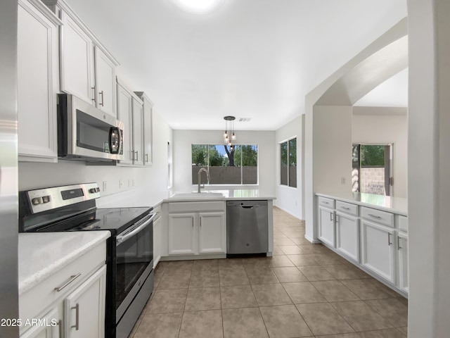4229 E Betsy Ln, Gilbert, AZ 85296 - kitchen with appliances with stainless steel finishes, a peninsula, light countertops, light tile patterned flooring, and white cabinetry