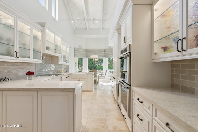 kitchen with beam ceiling, decorative backsplash, light stone countertops, and high vaulted ceiling