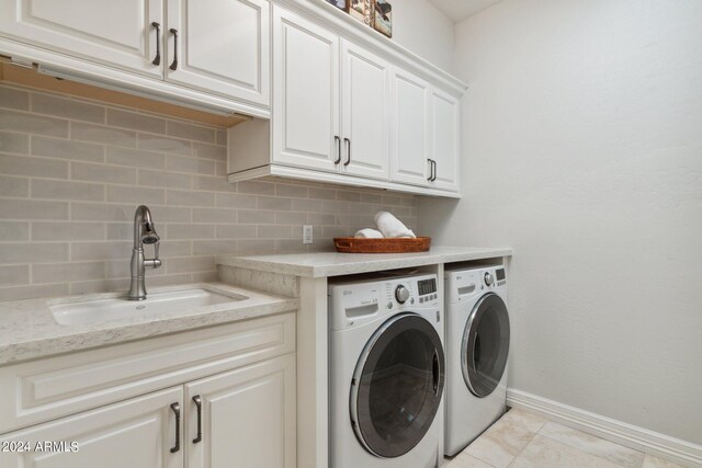 clothes washing area featuring light tile patterned flooring, cabinets, separate washer and dryer, and sink