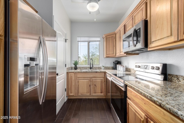 kitchen featuring sink, light stone counters, dark hardwood / wood-style flooring, ceiling fan, and stainless steel appliances