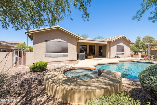 rear view of property with stucco siding, a pool with connected hot tub, fence, a patio area, and a tiled roof