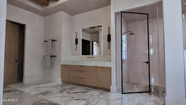 bathroom with a tile shower and vanity