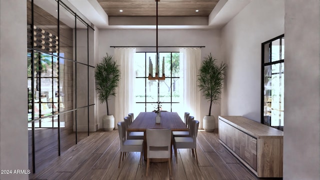 dining room featuring a raised ceiling, dark hardwood / wood-style flooring, wood ceiling, and a high ceiling