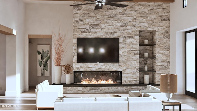 living room with hardwood / wood-style floors, a stone fireplace, a towering ceiling, and a wealth of natural light