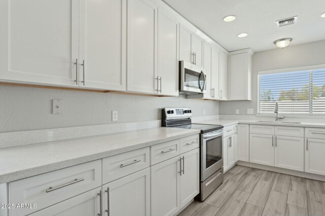 4634 W Aire Libre Ave, Glendale, AZ 85306 - kitchen with visible vents, a sink, light stone counters, stainless steel appliances, and white cabinets