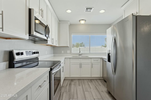 4634 W Aire Libre Ave, Glendale, AZ 85306 - kitchen featuring visible vents, a sink, appliances with stainless steel finishes, white cabinetry, and light wood-type flooring