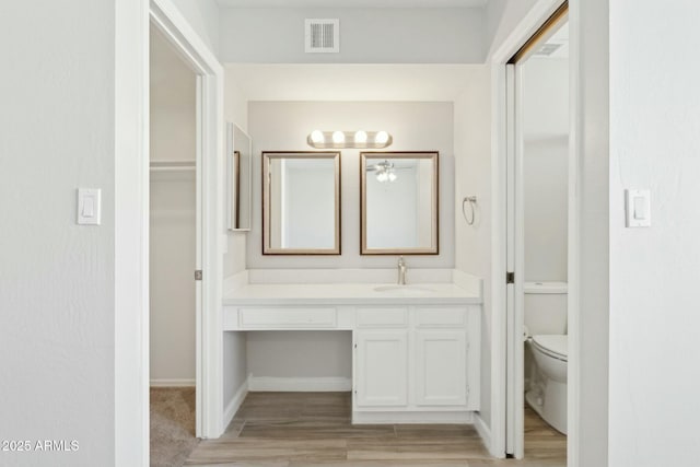 4634 W Aire Libre Ave, Glendale, AZ 85306 - bathroom featuring visible vents, baseboards, toilet, wood finished floors, and vanity