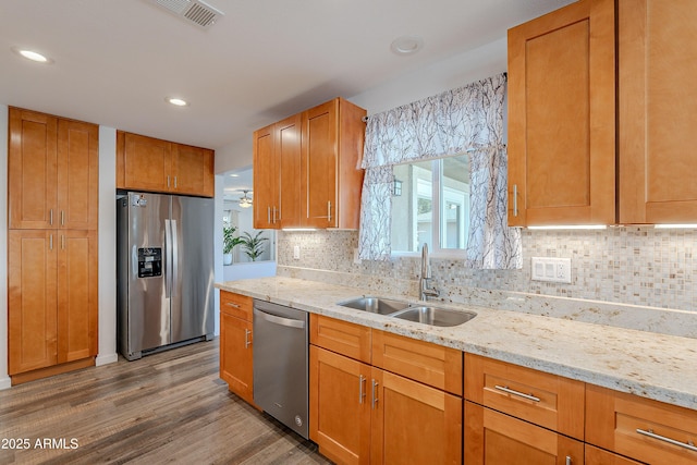 kitchen featuring light stone counters, sink, stainless steel appliances, and tasteful backsplash