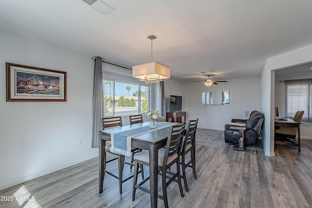 dining area featuring ceiling fan with notable chandelier and wood-type flooring