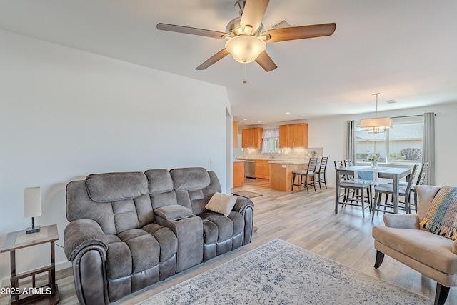 living room featuring ceiling fan, light wood-type flooring, and sink