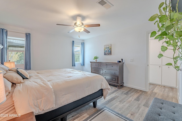 bedroom featuring ceiling fan, light hardwood / wood-style floors, and multiple windows