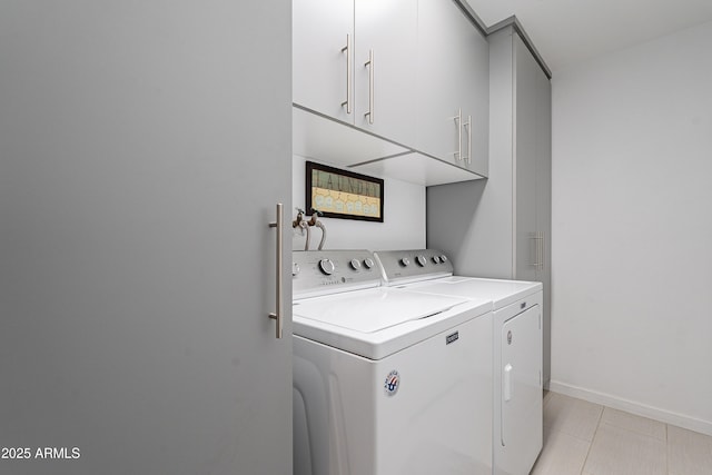 laundry area featuring washer and clothes dryer, light tile patterned flooring, and cabinets