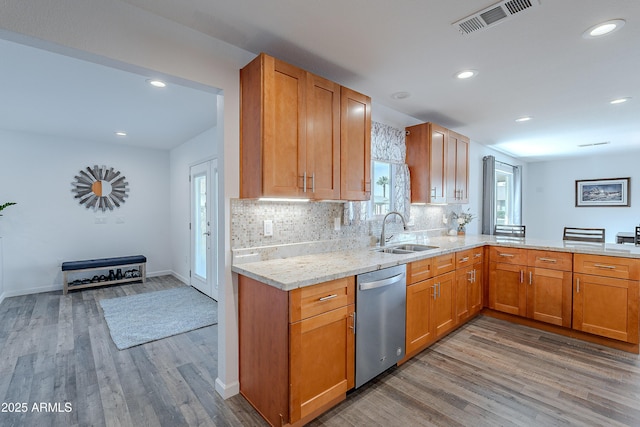 kitchen with light stone countertops, dishwasher, sink, backsplash, and light wood-type flooring