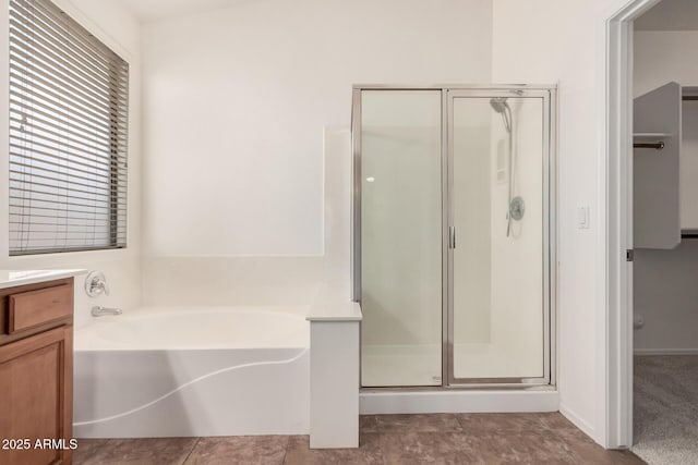 bathroom featuring a bath, vanity, and a shower stall
