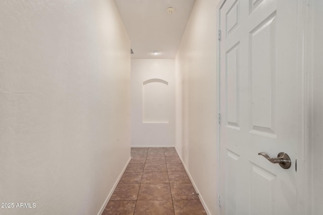 corridor with baseboards and dark tile patterned floors