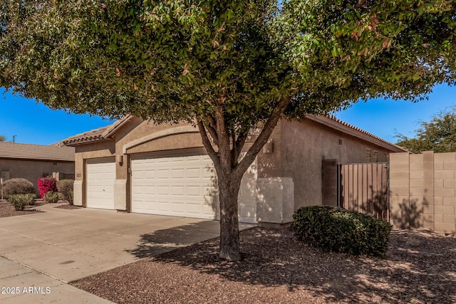 view of side of property featuring stucco siding, a tile roof, concrete driveway, and a garage