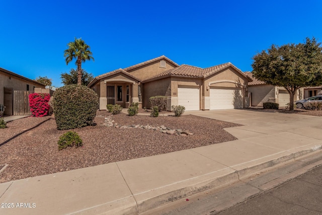 view of front facade with stucco siding, a tile roof, concrete driveway, and an attached garage