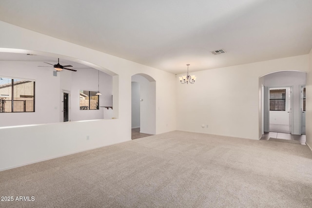 spare room featuring arched walkways, visible vents, light colored carpet, and ceiling fan with notable chandelier