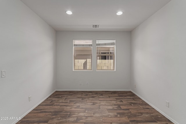 empty room featuring dark wood finished floors, visible vents, recessed lighting, and baseboards