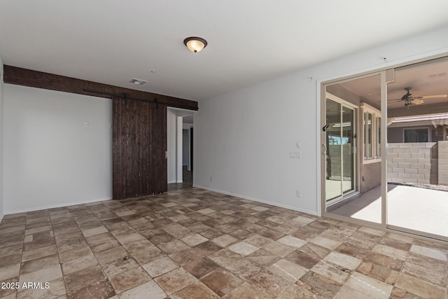 unfurnished room with visible vents, a ceiling fan, stone finish floor, a barn door, and baseboards