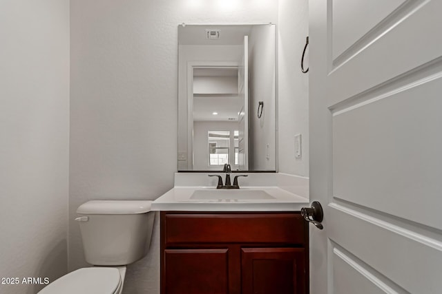 bathroom featuring vanity, toilet, and visible vents