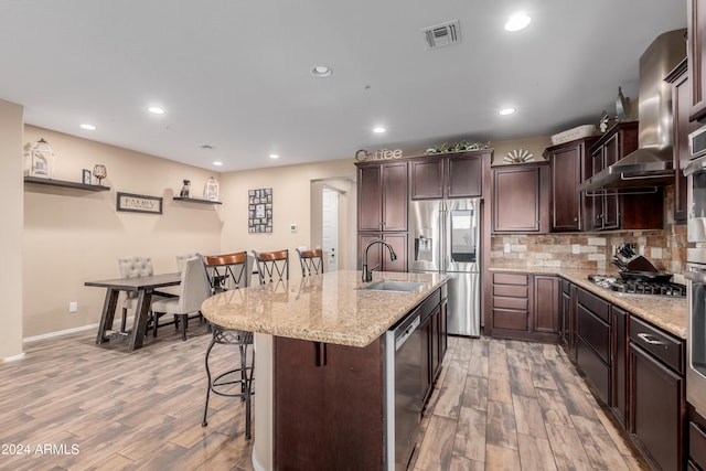 kitchen featuring light hardwood / wood-style flooring, a breakfast bar area, a center island with sink, and sink