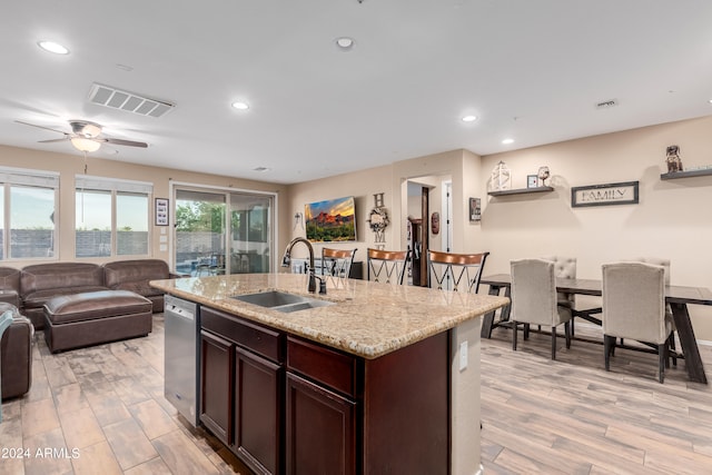 kitchen featuring light stone countertops, dark brown cabinets, light hardwood / wood-style floors, sink, and ceiling fan