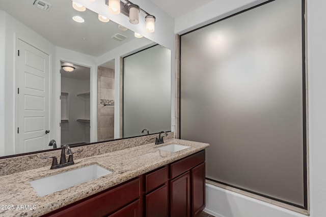 full bathroom featuring a sink, visible vents, walk in shower, and double vanity