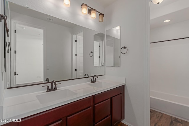 full bathroom featuring a sink, shower / bathing tub combination, wood finished floors, and double vanity