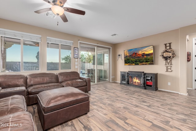 living room featuring ceiling fan, a fireplace, and light hardwood / wood-style floors