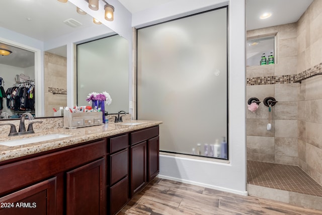 bathroom with tiled shower, vanity, and hardwood / wood-style flooring