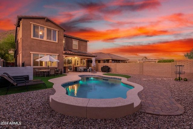 pool at dusk with a fenced in pool, a fenced backyard, and a patio area