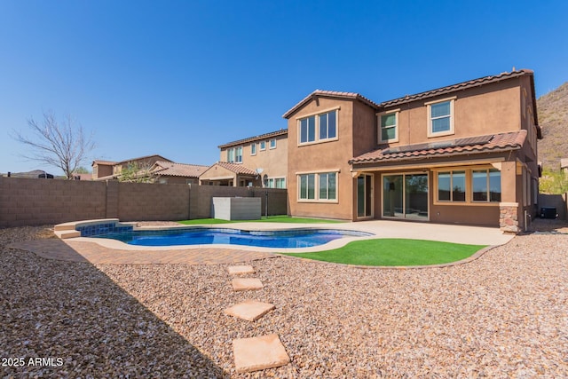 back of house featuring a patio area, a fenced backyard, a fenced in pool, and stucco siding