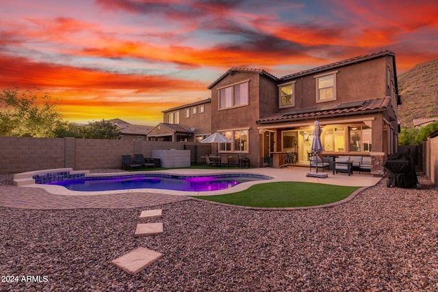 pool at dusk with an outdoor living space and a patio area