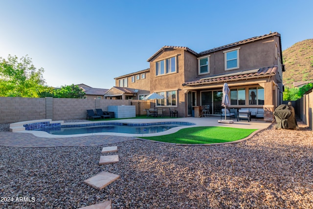 rear view of property with a fenced in pool and a patio area