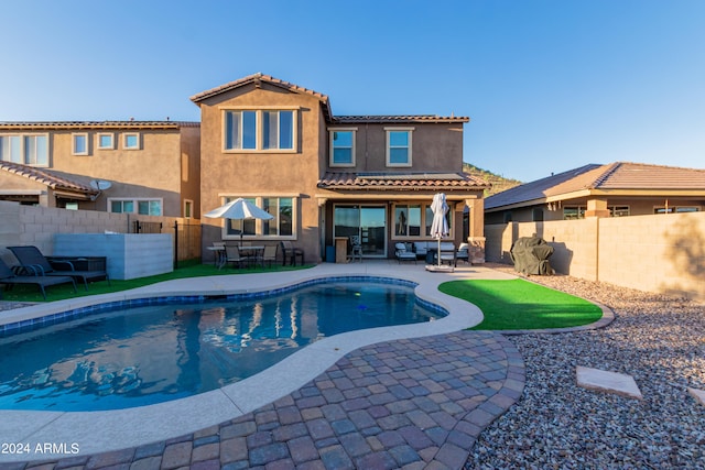 rear view of property with a fenced in pool and a patio area