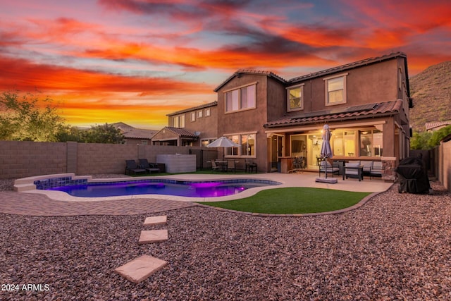 back of property with a tile roof, a fenced backyard, a fenced in pool, an outdoor hangout area, and a patio area