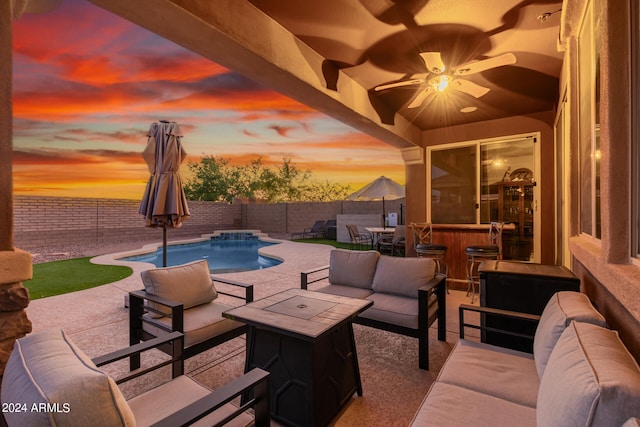 patio terrace at dusk with a fenced in pool, ceiling fan, and outdoor lounge area