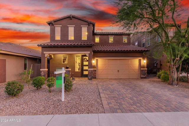 mediterranean / spanish-style home featuring decorative driveway, covered porch, a garage, and stucco siding