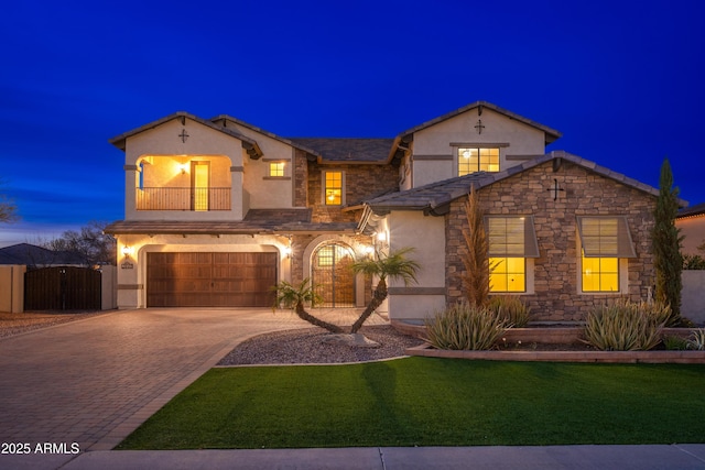 view of front facade featuring stucco siding, decorative driveway, a balcony, an attached garage, and a gate