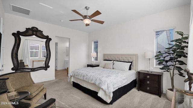 carpeted bedroom with ensuite bath and ceiling fan