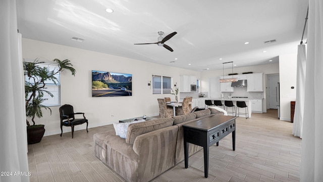 living room featuring ceiling fan and light hardwood / wood-style floors