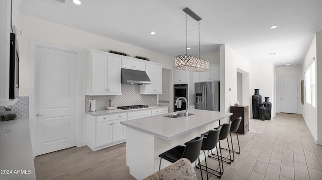 kitchen with white cabinetry, a kitchen island with sink, sink, and appliances with stainless steel finishes