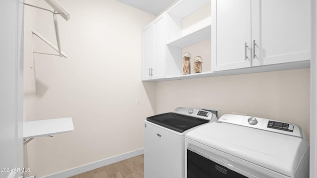 laundry area featuring cabinets, independent washer and dryer, and light hardwood / wood-style flooring