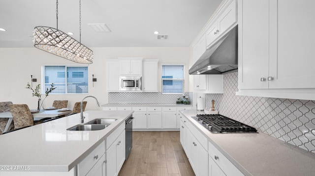 kitchen featuring appliances with stainless steel finishes, sink, pendant lighting, light hardwood / wood-style floors, and white cabinetry