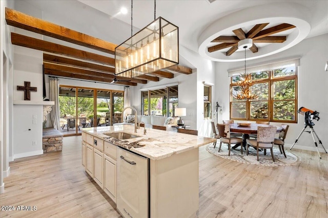 kitchen featuring beamed ceiling, light stone countertops, a sink, light wood-type flooring, and an island with sink